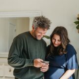 a man and a pregnant woman looking at a phone