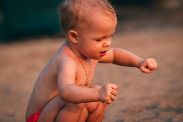 a toddler outside crouching down