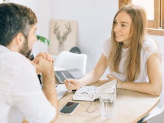 Premarital counseling Virginia A smiling woman and man having a friendly discussion at a table with a notebook and laptop