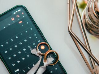 Premarital counseling Virginia Elegant setup of wedding rings on a smartphone displaying a calendar date, symbolizing planning and celebration